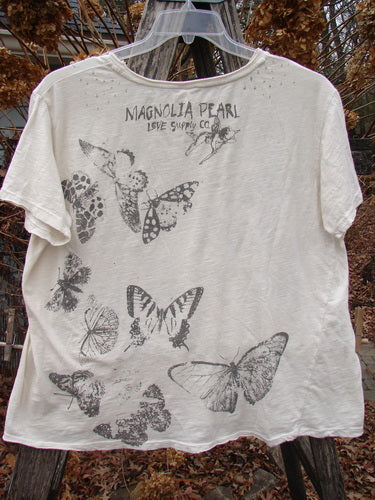 Magnolia Pearl NWT Cotton Jersey Boyfriend Tee Beyond Butterflies True OSFA, featuring black-and-white butterfly illustrations and MAGNOLIA PEARL LOVE SUPPLY CO. text, hanging on a clear plastic hanger outdoors.