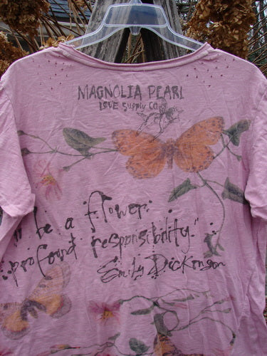 Magnolia Pearl NWT Cotton Jersey Boyfriend Tee Profound Responsibility Allium OSFA, featuring an orange butterfly, green leaves, and Emily Dickinson quote, highlighted by distressed shoulders and rolled edges, hung on a clear plastic hanger outdoors.