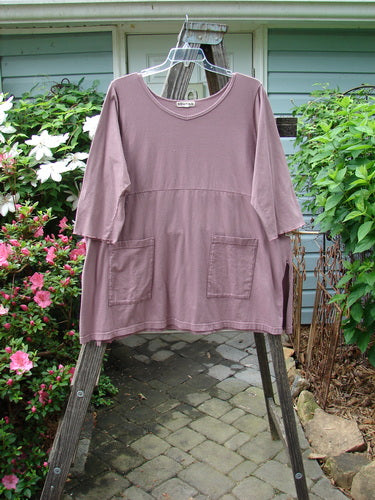 Barclay Empire Vented Pocket Top Unpainted Dusty Plum Size 2 displayed on a hanger, showcasing its rounded neckline, vented sides, exterior drop pockets, and three-quarter length sleeves.
