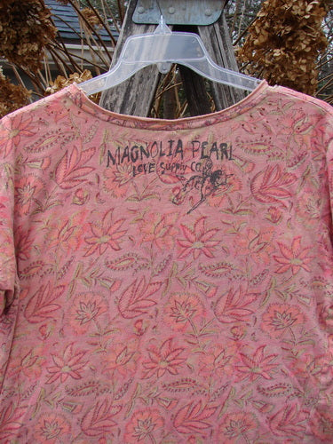 Magnolia Pearl NWT Cotton Jersey Boyfriend Tee Remi Block Print Sunset Flower OSFA, featuring a faded rose-pink distressed floral print, hangs on a clear hanger, showcasing its drapey feel and signature back branding.