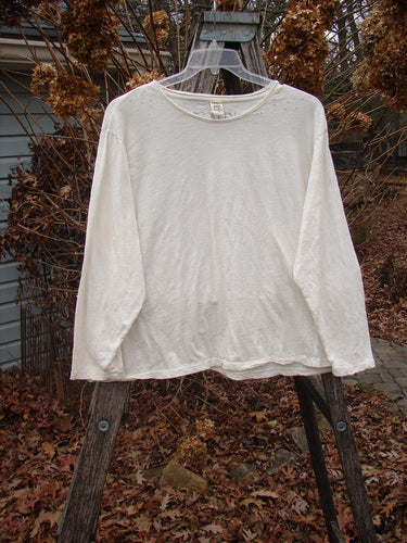 Magnolia Pearl Cotton Jersey Long Sleeved Boyfriend True OSFA hangs on a wooden ladder, showcasing its drapey, lightweight design with rolled edges and a distinctive reverse triangular wrap seam, embodying effortless, vintage-inspired style.