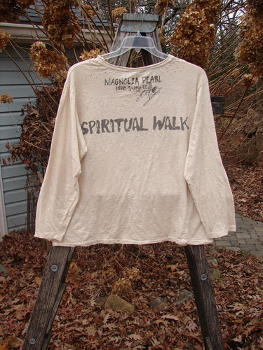 Magnolia Pearl NWT Cotton Jersey Boyfriend Tee Spiritual Walk Carousel OSFA drapes on a ladder, showcasing block-lettered SPIRITUAL WALK across the back, with distressed edges and a unique diagonal seam.
