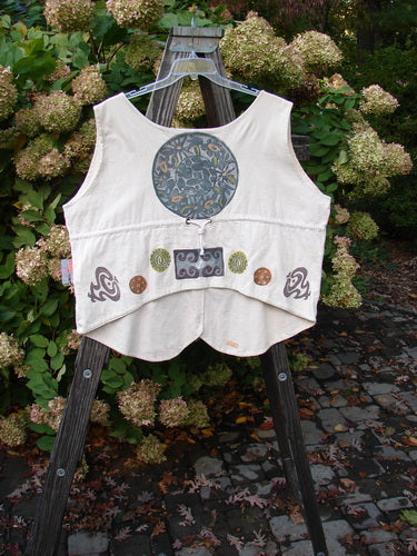 1993 The Vest Medallion Tea Dye Size 2: A white vest on a wooden stand with a blue and yellow flower design. Perfect oversized condition with tuxedo style front tails and a draw corded back. Vintage and hand-painted in the festive medallion theme.