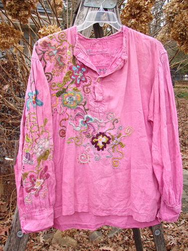 Magnolia Pearl Embroidered Linen Gypsy Johnny & Co Shirt Pinkster OSFA: A relaxed-fit, pink blouse with vibrant floral embroidery, featuring billowy sleeves, a criss-cross tab, and a distinct shirttail hemline.