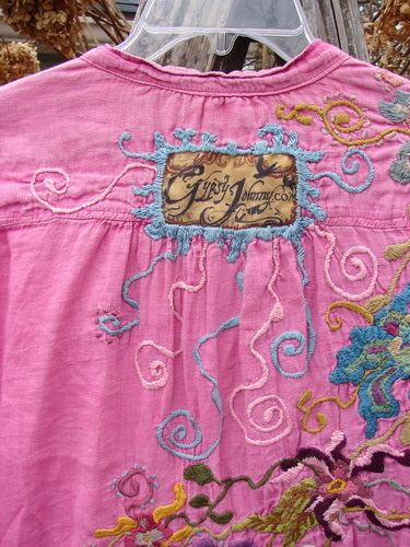 Back view of the Magnolia Pearl Embroidered Linen Gypsy Johnny & Co Shirt Pinkster OSFA, featuring intricate embroidery, a tan signature patch, and billowy sleeves, showcasing vintage-inspired, artistic detailing.