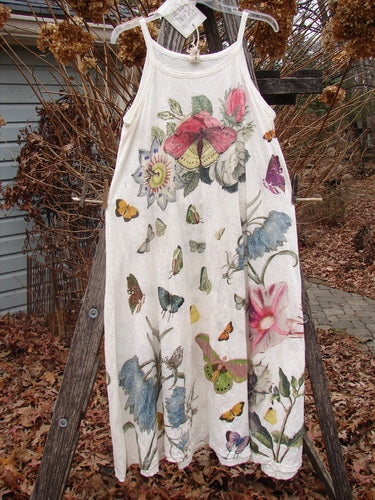 Magnolia Pearl NWT Cotton Jersey Lana Tank Dress Flor Da La Pasion True OSFA hangs outdoors, showcasing its colorful botanical and butterfly print, delicate spaghetti straps, and raw-edged A-line design.