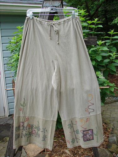 Barclay Cotton Hemp Drawstring Cuff Bottom Pant Asian Inspiration Wheat Size 0 hanging on a clothesline, showcasing detailed Asian-inspired patterns with a full drawcord waistline and paneled, weighted cuffs for optimal drape.