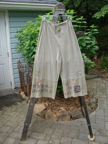 Barclay Cotton Hemp Drawstring Cuff Bottom Pant Asian Inspiration Wheat Size 0 displayed on a wooden ladder, showcasing the unique paneled cuffs and detailed Asian-inspired painted designs.