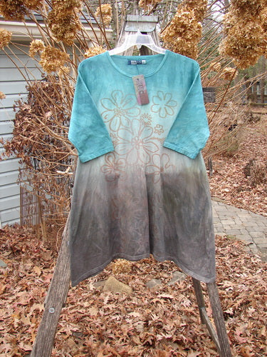 Barclay NWT Wander Tunic Tee Contour Daisy Logo Bolsena Size 0, featuring an aqua to gray gradient with a light tan floral motif, hanging on a wooden ladder outdoors.