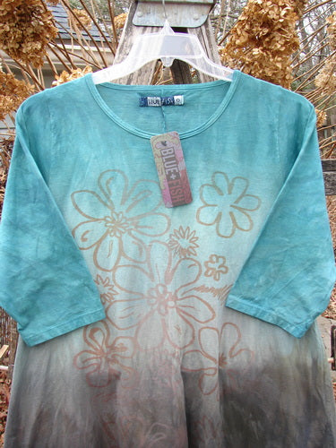 Barclay NWT Wander Tunic Tee Contour Daisy Logo Bolsena Size 0, featuring a teal-to-taupe ombré and tan floral motif, with three-quarter length sleeves and scoop neckline, hanging on a clear hanger.