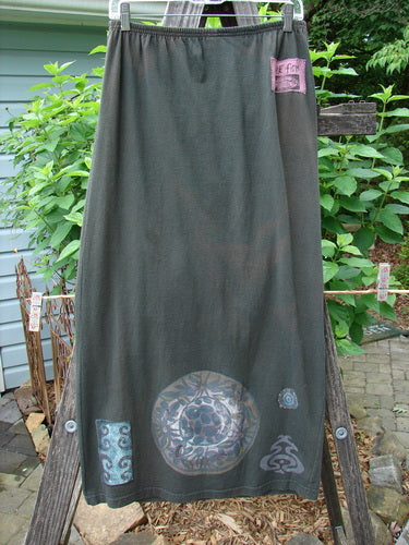 1992 Straight Skirt Holiday Metallic Medallion Black Sand Size 1 displayed on a wooden stand, showcasing its straightened shape and full elastic waistline with a continuous metallic medallion theme.