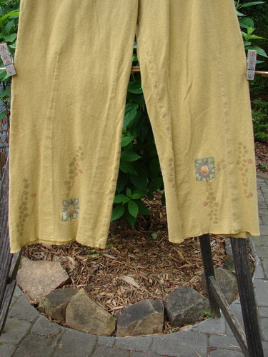 2000 Hemp Cotton Archive Pant Sun Gold Altered Size 0 hanging on a clothesline, showcasing its belled legs, elastic backing, paneled front, and sun-themed paint, reflecting its perfect condition and unique design.