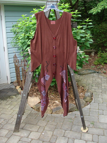 Barclay Calligrapher's Vest in Sepia with dramatic shape, deep V neckline, and vintage buttons draped over a wooden ladder.