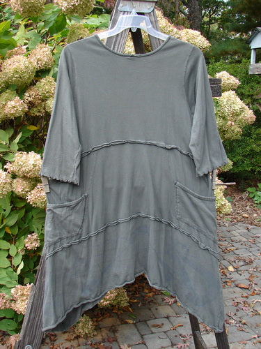 Barclay Cotton Lycra Raw Edge Vector Pocket Tunic Dot Grey Green Size 1 displayed on a clothes rack, featuring three-quarter sleeves, varying hemline, and two side pockets.