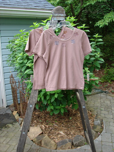 2000 Cotton Lycra Short Sleeved Layering Tops Necklace Coralline Size 1 displayed on a wooden rack, showcasing their fitted, shapely design and rounded neckline.