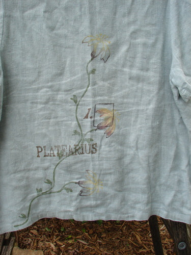 1998 Botanicals Robin's Top Platearius River Size 0: Close-up of white linen fabric with floral designs, highlighting the dual front pockets, seven buttons, and A-line shape.
