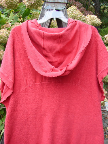 Barclay Celtic Moss Hooded Pocket Cardigan Unpainted Geranium Size 0 displayed on outdoor clothesline with floppy hood, short sleeves, two lower exterior pockets, and curly edgings, highlighting its textured, medium-weight fabric.