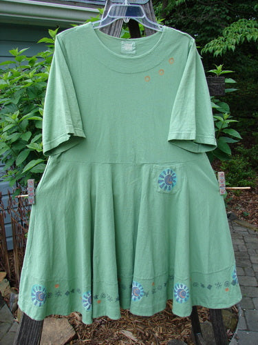 1999 Nest Dress Sun Border Spearmint Size 0 hanging outdoors, showcasing its paneled neck, short springy sleeves, and thick double-layered hemline. The dress features a painted sweet sun border theme and a tiny upper hip pocket.