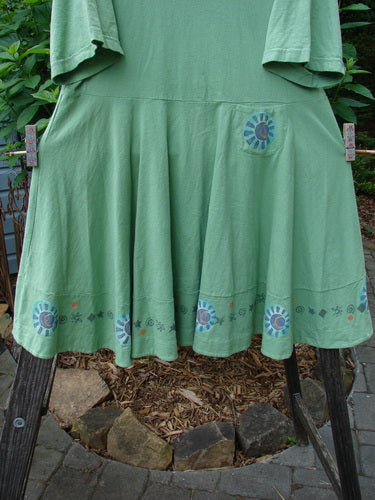 1999 Nest Dress Sun Border Spearmint Size 0: Green dress with a floral design, short sleeves, paneled neck, and a swingy lower hem adorned with a tiny painted hip pocket.