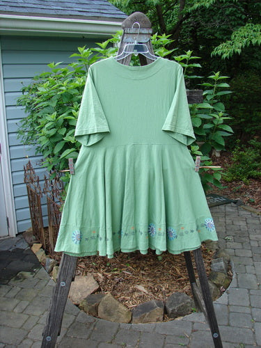 1999 Nest Dress Sun Border Spearmint Size 0 displayed on a clothes rack, showcasing its paneled neck, short springy sleeves, and swingy lower hem, perfect for movement.