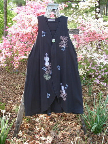 1996 State Fair Vest Music Festival Storm Size 1: Black, sleeveless, wrap-style vest with musical-themed appliqués, oversized button, unique hemline, captured outdoors against flowering shrubs, embodying Bluefishfinder's vintage aesthetic and creative freedom.