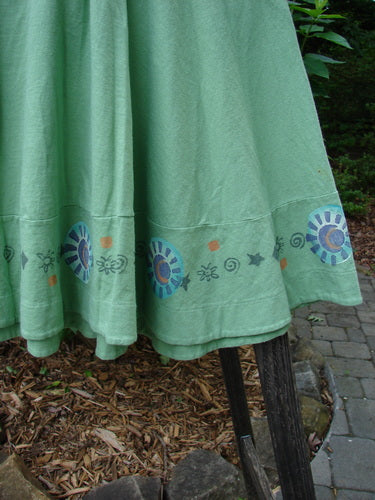 1999 Nest Dress Sun Border Spearmint Size 0, featuring a paneled neck, short sleeves, and a swingy lower with a painted sweet sun border theme and tiny upper hip pocket.