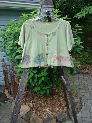 1993 Travel Top Beach Treasure Kelp Altered Size 2 displayed on a wooden rack, featuring a deeply scooped neckline, crop shape, beach-themed design, and unique wooden buttons.