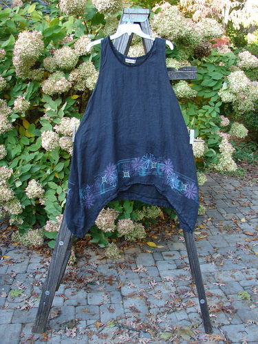 Barclay Linen Lace Pinafore Jumper Daisy Border Black Size 0 displayed on a wooden ladder, showcasing its rounded dipped neckline, deeper arm openings, and varying dip side hem with daisy border design.