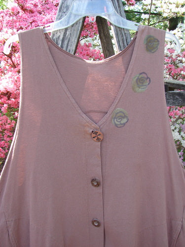 1993 Short Column Vest Floral Vine Rosewood OSFA hanging outdoors, showcasing its sleeveless, V-neck design, decorative buttons, and hand-painted rose motifs on the shoulder. The vest features a swingy shape and front kangaroo pockets.