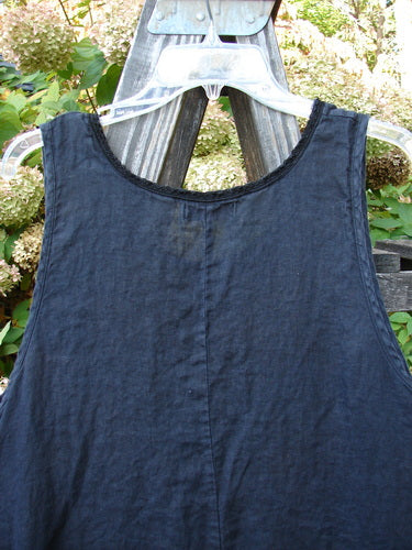 Barclay Linen Lace Pinafore Jumper Daisy Border Black Size 0 displayed on a hanger, showcasing its rounded neckline, lace accents, and varying dip side hem with a daisy border design.