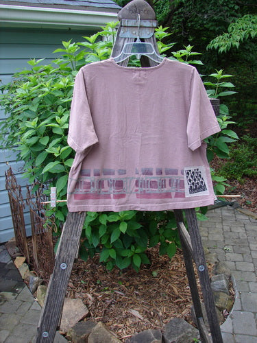 2000 Short Sleeved Crop Tee Mosaic Window Coralline Size 1 displayed on a wooden rack, showcasing its wide crop box shape and sweet mosaic window theme paint.