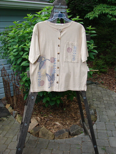 1994 Camp Shirt Berry Fern Garden Flaxen Altered Size 1 displayed on a rack, showcasing its oversized breast pocket, drop shoulders, varying hemline, and detailed fern garden theme paint.
