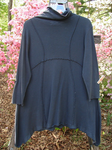 Barclay Thermal Reverse Stitch Pocket Dress in Raven, featuring a cozy cowl neckline, princess seams, asymmetric hem, and front drape pockets, hanging outdoors, embodying Bluefishfinder.com's vintage style.