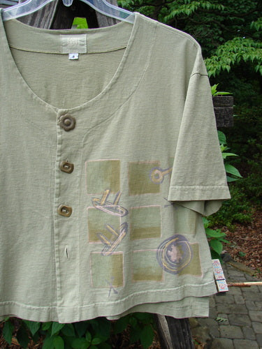 2001 Button Crop Top Junk Drawer Kelp Size 0, featuring wide short sleeves, cool buttons, a vented hemline, and a unique painted design, showcased in a close-up view highlighting its intricate details.