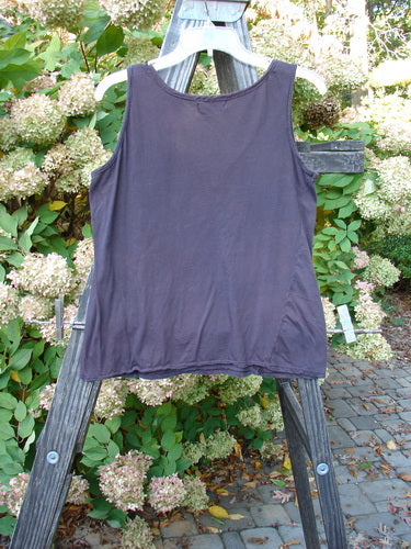 Barclay Batiste Decora Tiny Tank Unpainted Deep Burgundy Size 1 displayed on a wooden ladder in an outdoor garden setting, highlighting its vertical neckline tie and A-line shape.