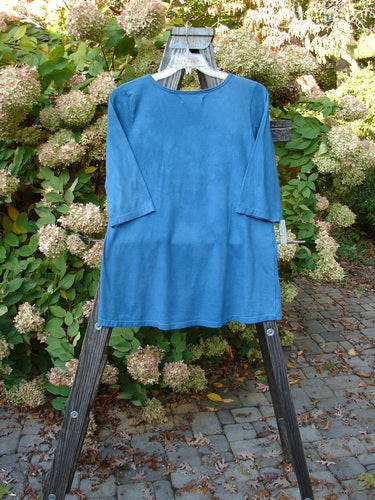Barclay NWT Modern Slim Tee Top Pansy Mottled Teal Size 1 displayed on a wooden clothes rack, showcasing its three-quarter sleeves, lower hip flare, and rounded hemline.