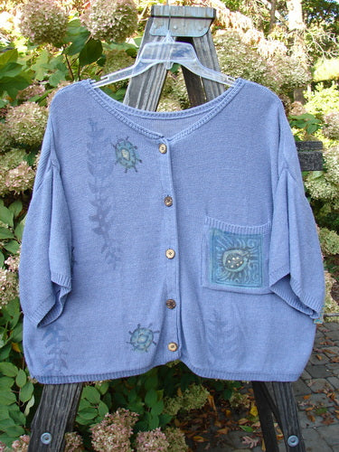1995 Cotton Rayon Short Sleeved Cardigan Sweater Friendly Garden Dusk Mélange Size 3 displayed on a hanger, featuring colorful buttons, wide sleeves, and varied stitch patterns with garden critter motifs.
