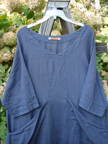 Barclay Linen Rear Tab Pocket Dress in Dusk Florals Dusty Navy Size 1 displayed on a hanger outdoors, showcasing its scooped neckline, pleated sleeves, and angular pockets.