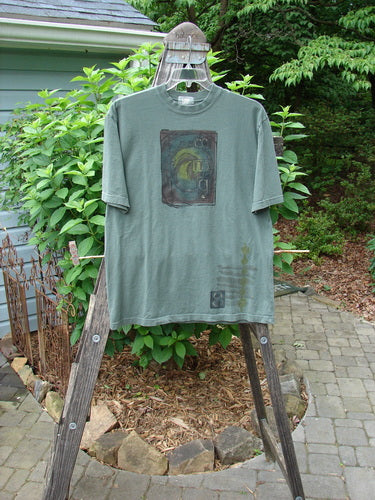 2000 Short Sleeved Tee Celtic Letter Park Size 1 displayed on a wooden rack, showcasing its drop shoulders, longer straight shape, and classic Celtic letter theme.