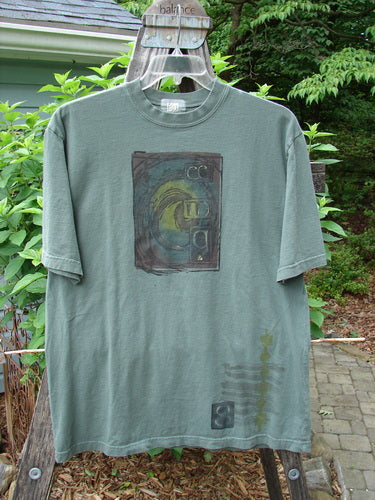 2000 Short Sleeved Tee Celtic Letter Park Size 1 displayed on a hanger, featuring a thicker ribbed neckline, drop shoulders, and a longer straight silhouette, showcasing a classic Celtic letter theme.