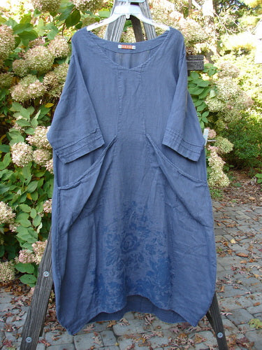 Barclay Linen Rear Tab Pocket Dress in Dusk Florals Dusty Navy Size 1, displayed on a wooden rack, showcasing its unique scooped neckline, pleated sleeves, and angular pockets, highlighting vintage Blue Fish Clothing style.