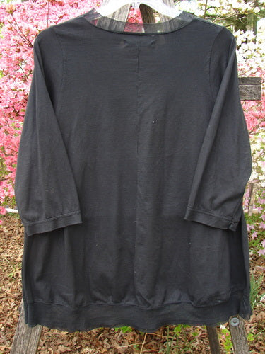 Barclay Flutter Edged Essential Tee in Lightning Black, hanging on a ladder. Features include a raw-edged mesh neckline, three-quarter sleeves, and a slight A-line shape.