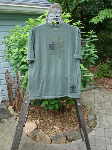 2000 Short Sleeved Tee Celtic Letter Park Size 1 displayed on a wooden ladder, showcasing its slightly thicker ribbed neckline, drop shoulders, and longer generous straight shape.