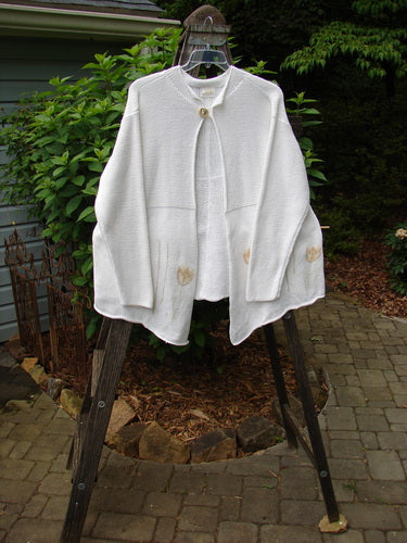 1999 Rollneck Cardigan Sweater Pastel Tulip Pure White OSFA displayed on a rack, featuring dual knitting, sectional rolled seams, varying hemline, cropped back, and porcelain buttons with stitched loops.