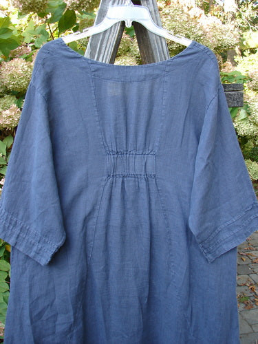 Barclay Linen Rear Tab Pocket Dress in Dusk Florals, Dusty Navy Size 1, on a clothes rack. Features scooped neckline, pleated sleeves, and angular pockets, showcasing vintage-inspired design from BlueFishFinder.com.