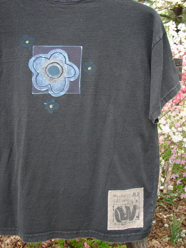 1997 Short Sleeved Tee Butterfly Ebony Size 0 features a hand-painted blue-green floral motif on the back, displayed outdoors. Includes a signature patch, showcasing Blue Fish's vintage creative expression.
