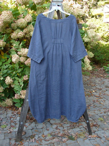 Barclay Linen Rear Tab Pocket Dress in Dusk Florals, Dusty Navy, Size 1, displayed on a clothes rack, showcasing its wider neckline, pinched sleeves, and unique hemline.