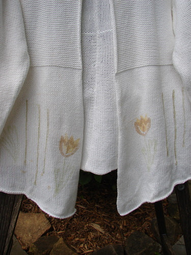 1999 Rollneck Cardigan Sweater in Pure White with pastel tulips, featuring dual knitting, sectional rolled seams, and a varying hemline. Cropped back and double shiny porcelain button closure.
