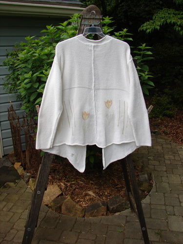 1999 Rollneck Cardigan Sweater Pastel Tulip Pure White OSFA displayed on a hanger, showcasing dual knitting, sectional rolled seams, varying hemline, cropped back, and double shiny porcelain button with pastel tulip accents.