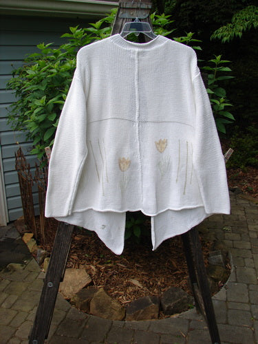 1999 Rollneck Cardigan Sweater Pastel Tulip Pure White OSFA displayed hanging outdoors, featuring dual knitting, rolled seams, and pastel tulips with a double shiny porcelain button closure.